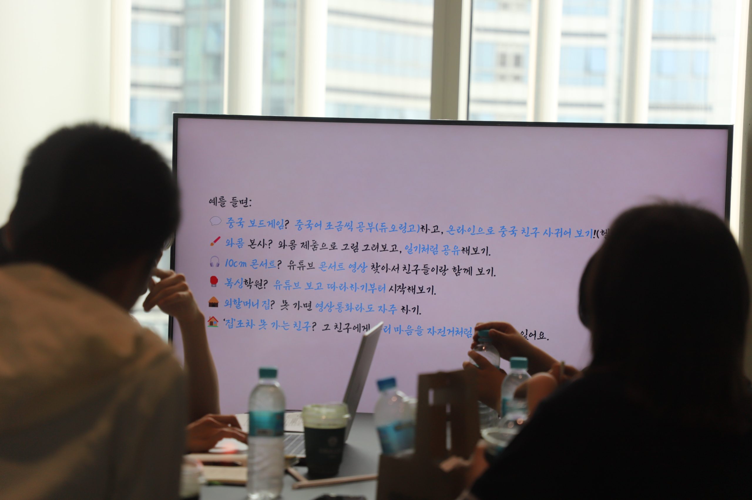 멘토링 현장 사진, 회의실 모니터에 교육 내용이 보이고 학생들이 집중하고 있는 모습